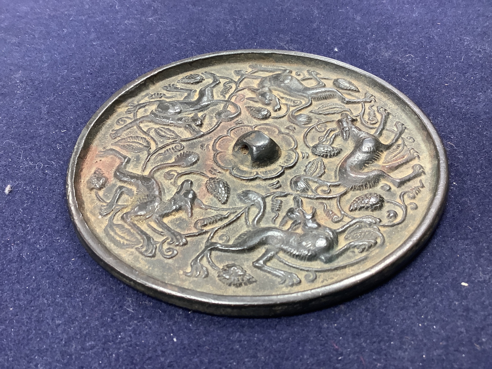 A Chinese bronze mirror, cast with vines and hounds, 14cm